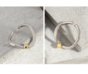 Macro shot of minimalist silver S925 ring featuring a small gold bead detail