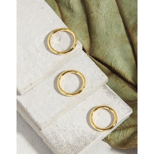 Set di anelli minimalisti placcati in oro su sfondo in pietra naturale con foglie