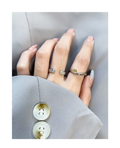 Detail of silver S925 rings featuring blue gemstone and gold bead on wave band