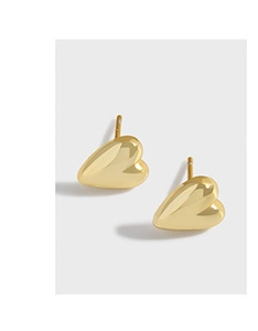 Macro side view of polished gold heart stud earrings with a glossy mirror finish