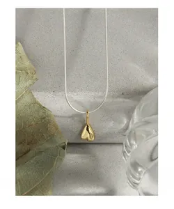 Macro shot of 3D gold heart pendant with sleek silver snake chain on textured background