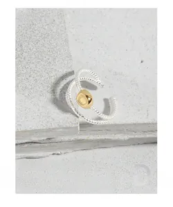 Détail de la bague torsadée en argent S925 avec perle dorée sur un support en pierre