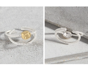 Détail macro de la bague torsadée en argent S925 avec une perle centrale dorée polie