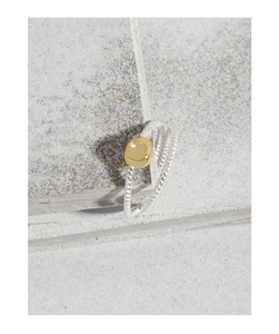 Détail d'une bague tressée en argent avec un bloc carré irrégulier en or poli au centre