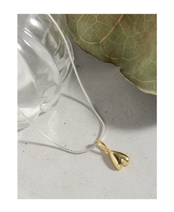 Detailed shot of a gold heart pendant on a silver snake chain over a textured stone surface