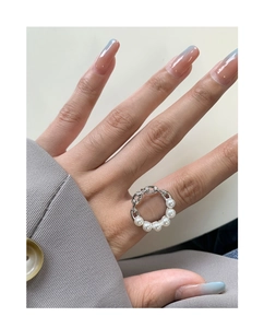 Detail shot of a S925 silver chain ring with white pearls on a woman finger