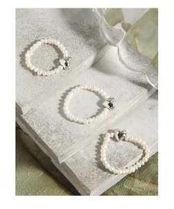 Close-up of three handmade natural pearl rings with heart-shaped silver metal charms