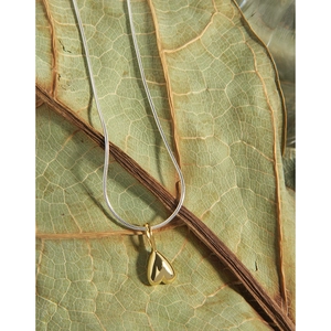 Two-tone S925 silver snake chain necklace with a 3D gold heart pendant on natural leaves
