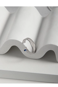Macro detail of textured silver ring with micro-set rectangular blue zircon stone