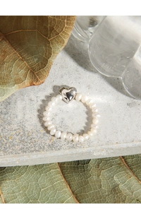 Detail of freshwater pearl beaded ring with a polished silver heart charm centerpiece