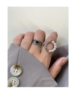 Close-up of S925 silver stacked rings with black heart and pearl chain on female hand