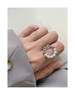 Detail of S925 silver chain ring with six white pearls worn by a model in gray outfit