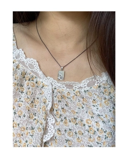 Close-up of S925 silver necklace with textured rectangular pendant on a female model