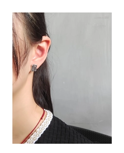 Close-up of silver irregular rectangular stud earrings with hammered metal texture