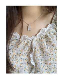 Detail of silver S925 geometric pendant necklace with textured surface on a female model