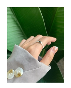Detail shot of a natural pearl beaded ring with a silver heart charm on a finger