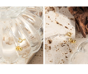 Detail of silver paperclip chain bracelet with golden beads and round spring clasp