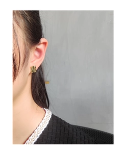 Detail of gold geometric square stud earrings with irregular hammered texture on model
