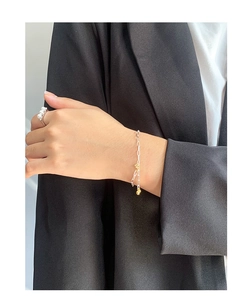 Detail of minimalist S925 sterling silver chain bracelet with gold bead on model wrist