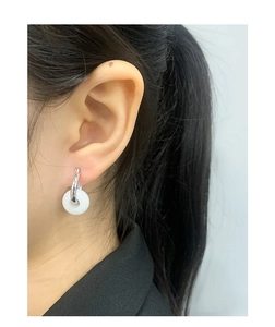 Detail view of S925 silver hoop earring with white round jade-like pingan pendant on ear