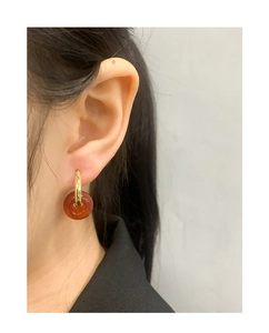 Detail of elegant gold hoop earrings with translucent red-brown agate stone pendant charms