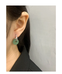 Close-up of S925 silver hoop earrings with translucent green jadeite charm on ear