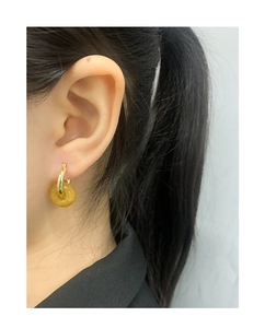 Close-up of a model wearing minimalist gold hoop earrings with yellow translucent circles