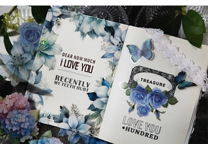 Close-up of blue floral stickers with gold foil details on a notebook page decoration