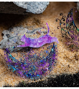 Detail of holographic PET cat stickers with moon and mandala motifs on a rock background