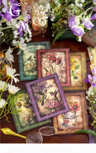 Vintage floral scrapbooking paper stack with butterfly and rabbit motifs on dark wood