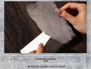 Detail showing vintage decorative paper being hand-torn for scrapbooking and DIY journals