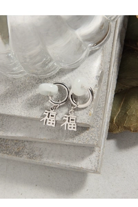 Macro detail of S925 silver earrings with jade bead and Fu character pendant charm