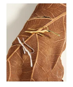 Macro shot of S925 silver organic twig earrings in gold and silver on a dried leaf
