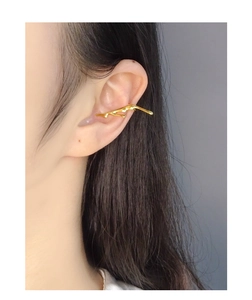 Close-up of golden irregular liquid lava ear cuff with organic metal finish on ear