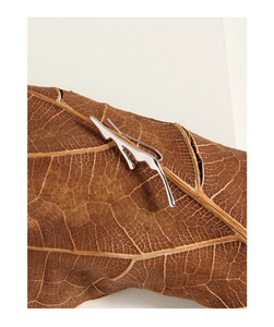 Detailed close-up of liquid lava style silver earrings on a natural dried autumn leaf