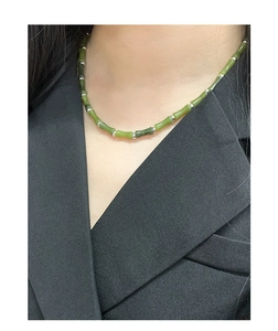 Detail of bamboo joint jade necklace with S925 silver beads worn on a black suit