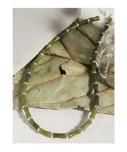 Detailed shot of bamboo joint necklace with natural olive jade beads on autumn leaves