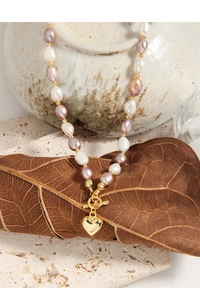 Detailed view of Baroque pearl necklace with gold heart pendant on toggle clasp