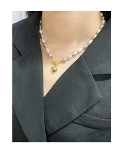 Close-up of baroque pearl heart necklace with OT toggle clasp worn on professional attire
