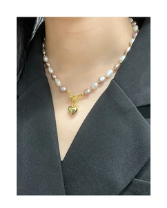 Detail of pink and purple baroque pearl heart necklace worn on a black blazer
