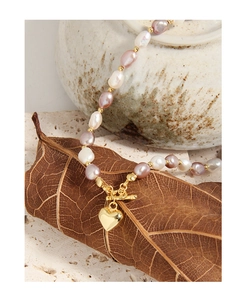 Detail of pink and purple baroque pearl heart necklace with OT clasp on dry leaves
