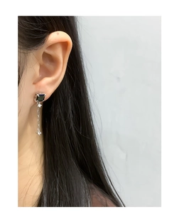 Vue détaillée d'une boucle d'oreille en argent avec pierre noire et chaîne à franges