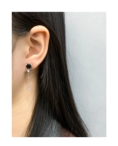Détail d'une boucle d'oreille longue en argent avec pierre noire et gemmes claires