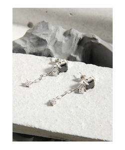 Détail macro d'une boucle d'oreille en argent S925 avec pierre noire et chaîne