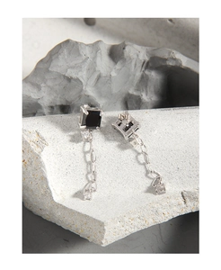 Détail de boucles d'oreilles en argent avec pierre noire carrée et chaîne en zircon