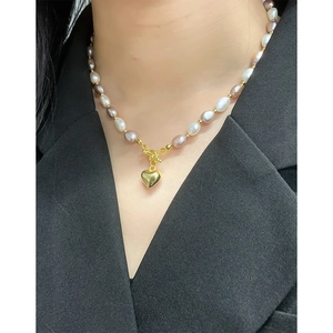 Pink and white baroque pearl necklace with gold heart pendant and OT buckle on model