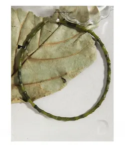 Détail des perles de jade en forme de bambou vert sur un collier à fermoir argent