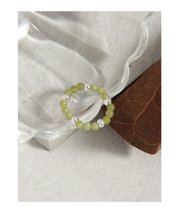 Détail de bague en argent S925 avec perles de jade vert émeraude sur une surface en pierre
