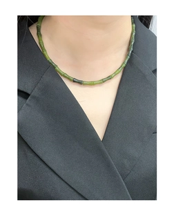 Détail du collier en jade vert foncé avec motif bambou sur un col de veste noir