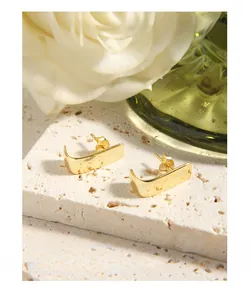 Close-up of polished gold rectangular curved earrings with S925 sterling silver posts